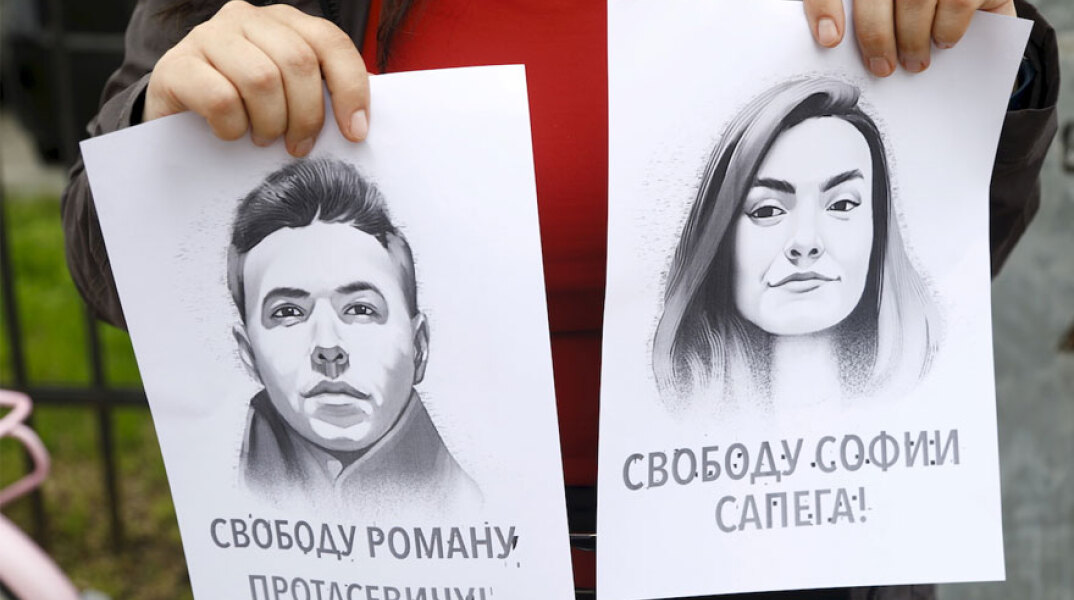 Κοπέλα σε παράσταση διαμαρτυρίας για τη Λευκορωσία κρατά σκίτσα με τον δημοσιογράφο Ρόμαν Προτάσεβιτς και τη σύντροφό του, Σοφία Σαπέγκα