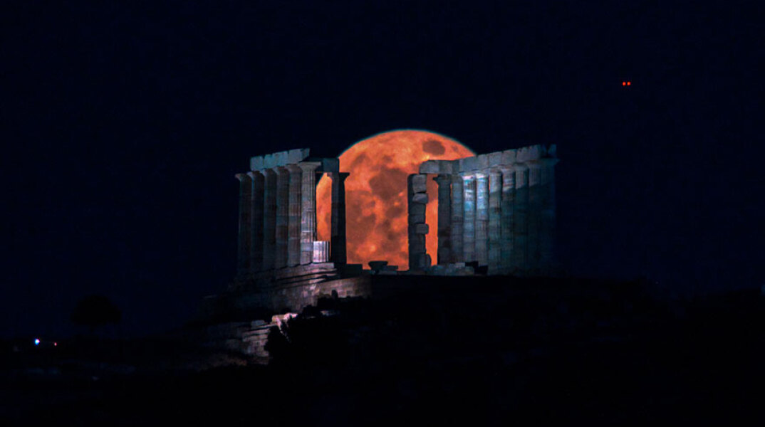 Η «ματωμένη» υπερπανσέληνος του Μαΐου ξεπροβάλλει πίσω από τον ναό του Ποσειδώνα στο Σούνιο