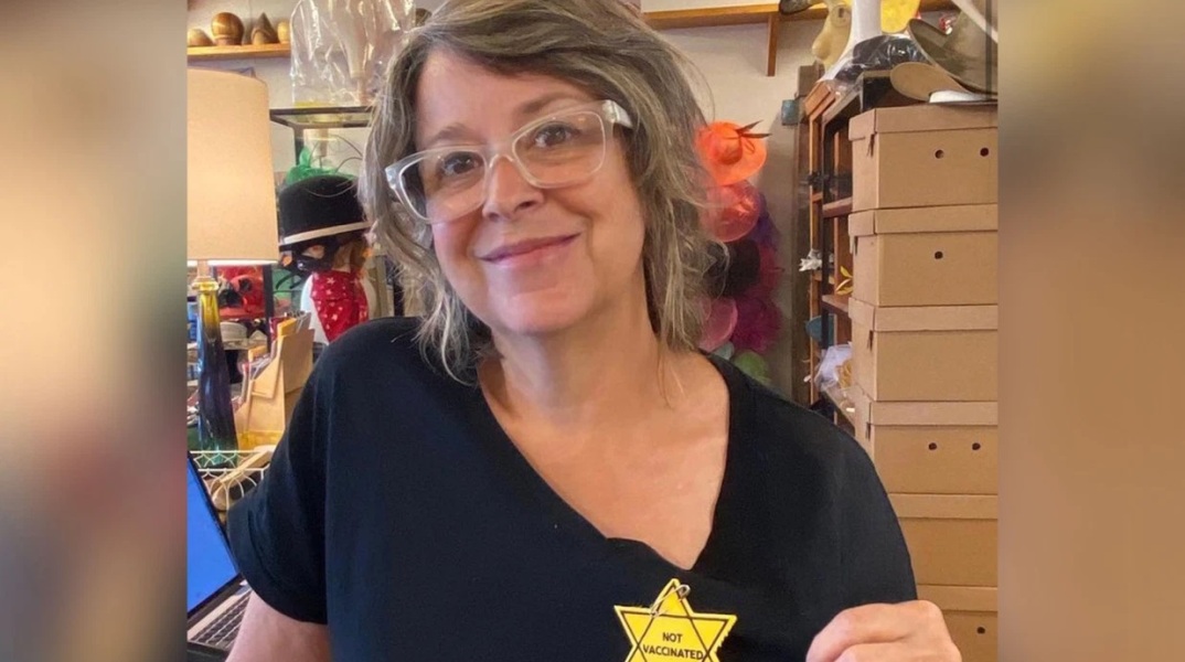 Γυναίκα φορά αυτοκόλλητο κίτρινο αστέρι με την ένδειξη «Δεν είμαι εμβολιασμένος»