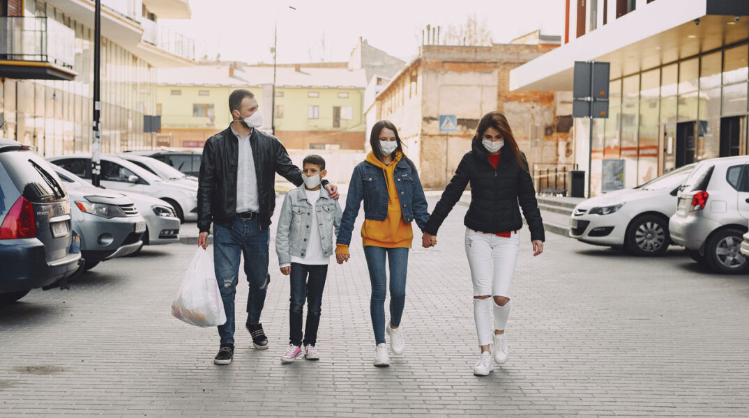 Οικογένεια πιασμένη από το χέρι περπατάει στο δρόμο