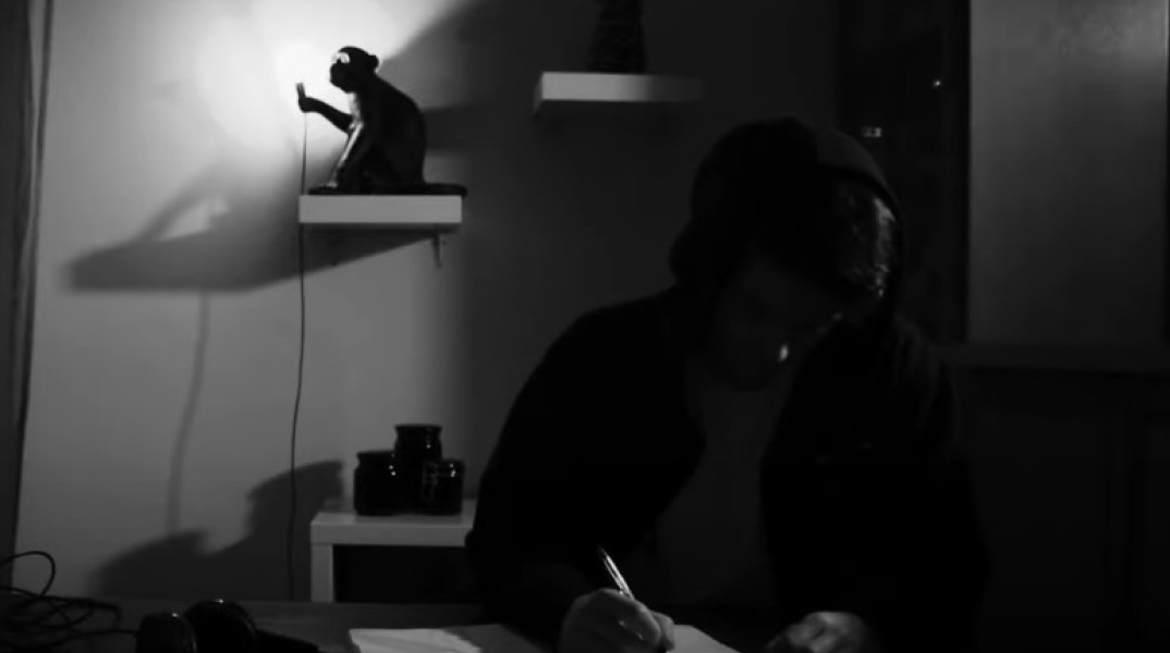 Άνδρας που γράφει σημειώσεις σε τετράδιο - Στιγμιότυπο από βιντεοκλίπ των Qimera