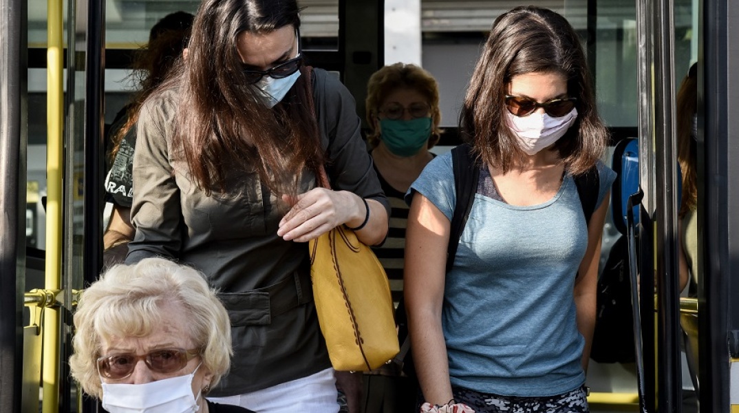 Πολίτες με μάσκα βγαίνουν από λεωφορείο