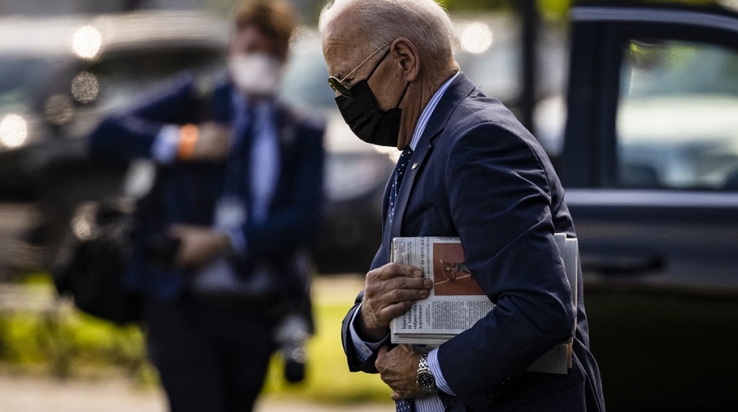 Ο πρόεδρος των ΗΠΑ Τζο Μπάιντεν με μάσκα προστασίας και γυαλιά ηλίου κρατά εφημερίδα