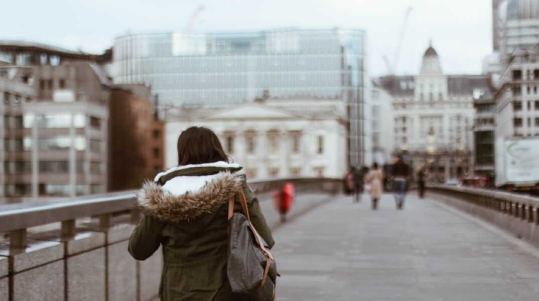Μια κοπέλα περπατάει στη γέφυρα του Λονδίνου©Unsplash/ Sincerely Media