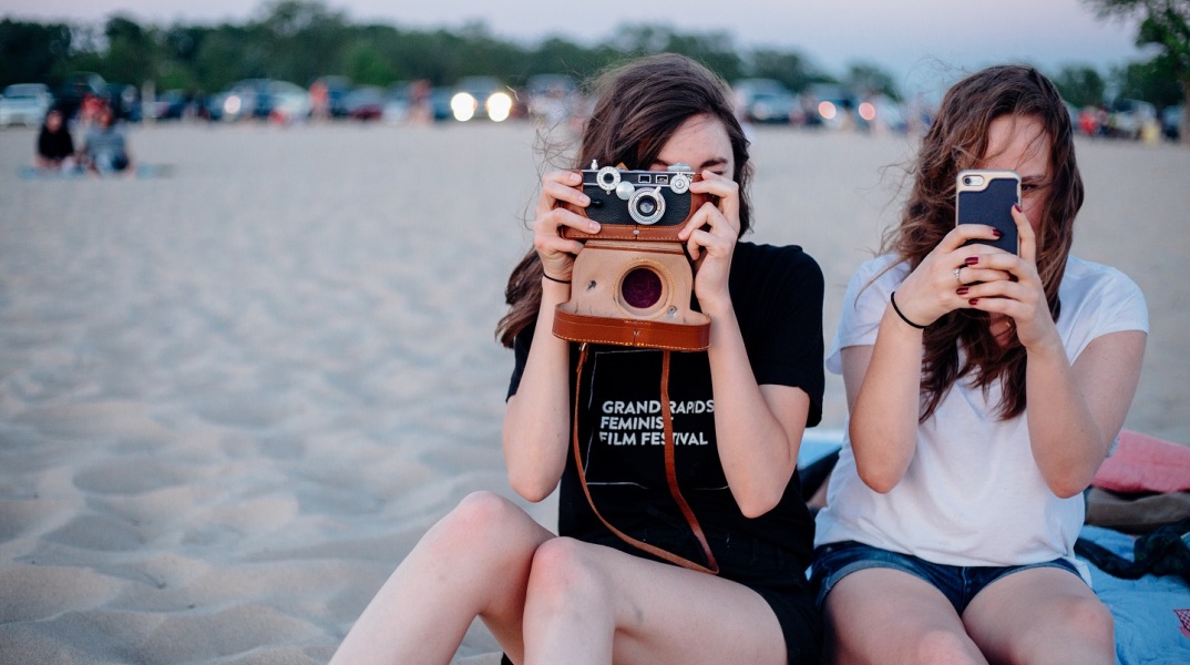 Γυναίκες σε θάλασσα που φωτογραφίζουν με φωτογραφική μηχανή και smartphone