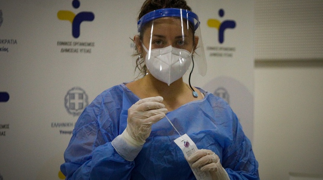 Γυναίκα διενεργεί rapid test φορώντας μάσκα και γάντια