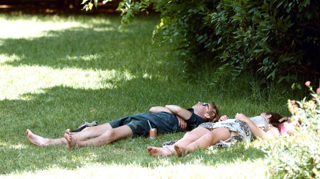 Ζευγάρι ξαπλωμένο στο γρασίδι στο κέντρο της Αθήνας©ΑΠΕ/ΠΑΝΤΖΑΡΤΖΗ Σ