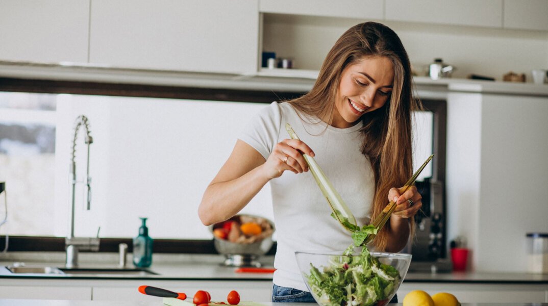 Γυναίκα σε κουζίνα φτιάχνει σαλάτα