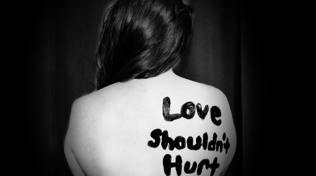 Γυναίκα που έχει γραμμένο στην πλάτη της το σύνθημα «Η αγάοη δεν πληγώνει» © Unspalsh