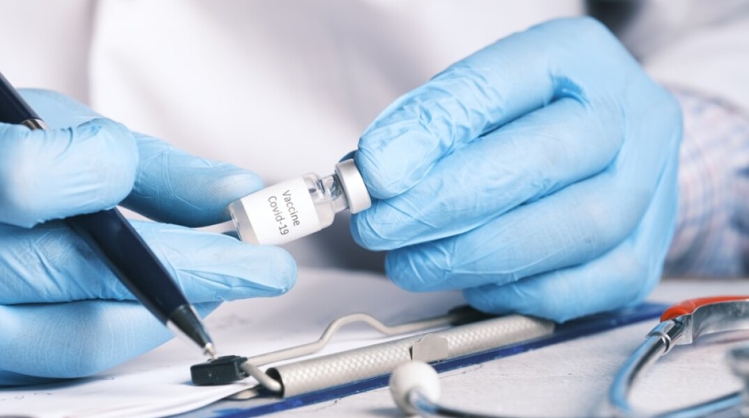 Γιατρός με γάντια μιας χρήσης κρατάει φιάλη με εμβόλιο και σύριγγα © Unsplash