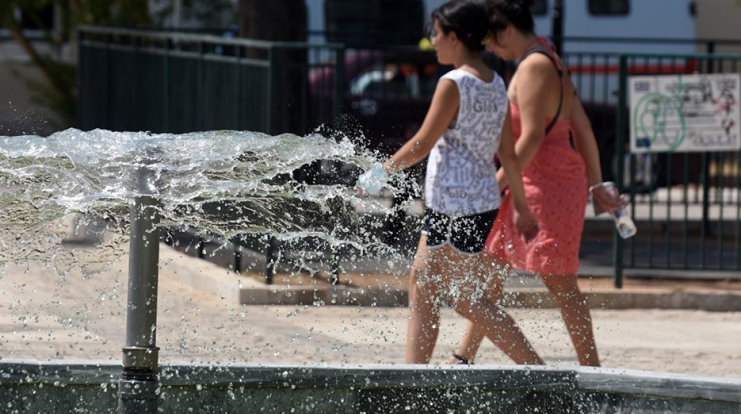 Καύσωνας - Γυναίκες περπατούν μπροστά από σιντριβάνι