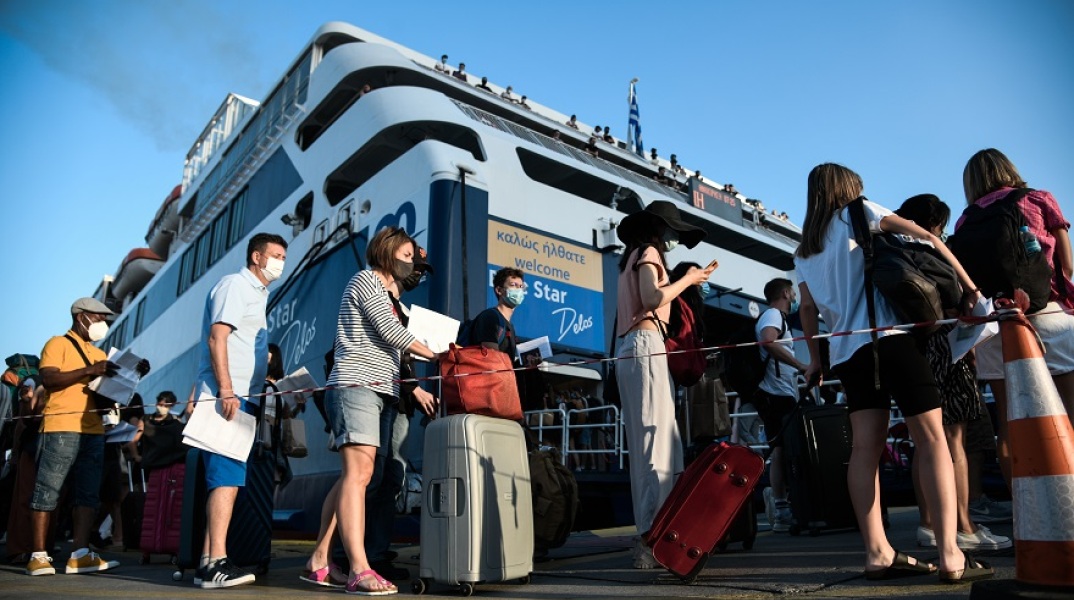 Ταξιδιώτες αναμένουν την επιβίβασή τους σε πλοίο κρατώντας στα χέρια κινητό ή έγγραφα που χρειάζονται