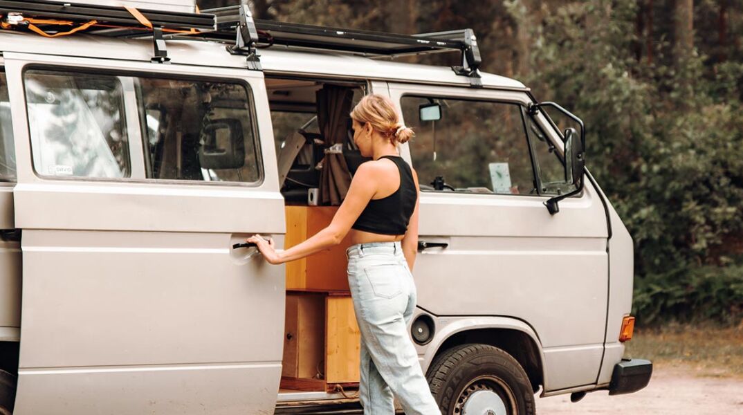 Κοπέλα με τζιν και μαύρη μπλούζα μπροστά από βανάκι στη φύση