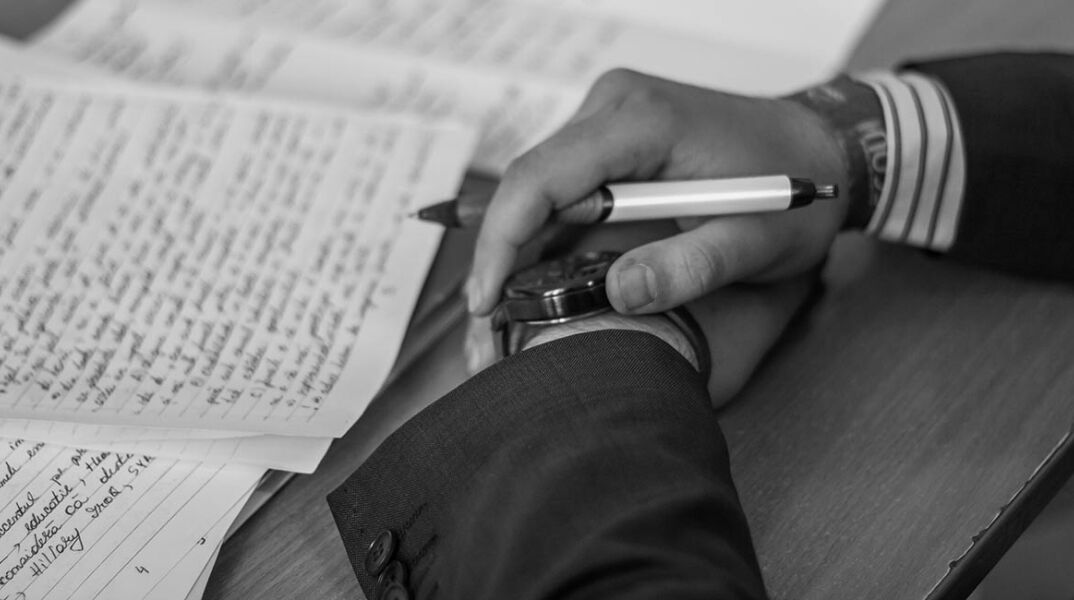 Άντρας με σταυρωμένα χέρια πάνω σε χαρτιά