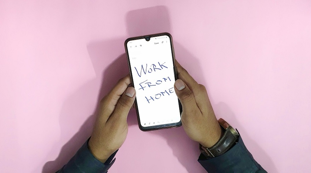 Smartphone στο οποίο αναγράφεται η φράση Work From Home