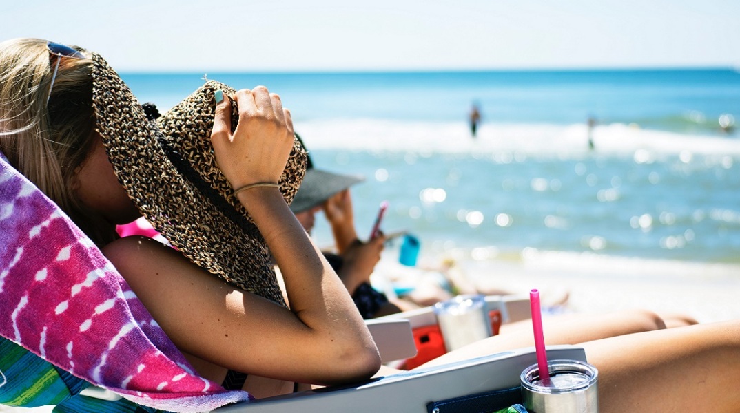Μια κοπέλα απολαμβάνει τον ήλιο στην παραλία.