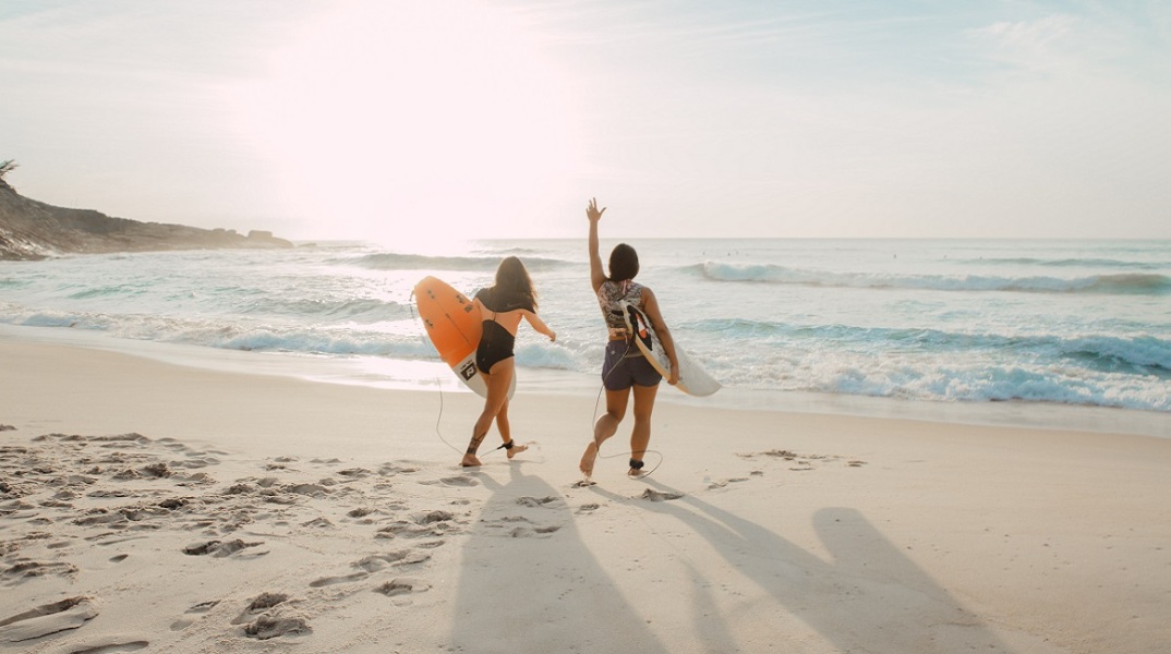 Κορίτσια ετοιμάζονται να βουτήξουν με τη σανίδα του surf στην παραλία.