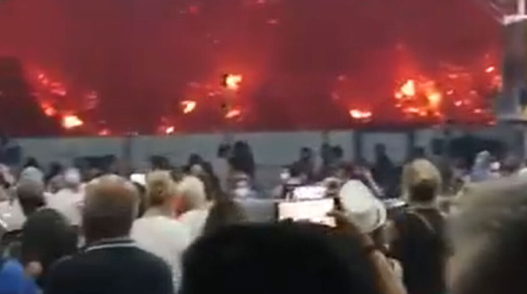 Φωτιά στην Εύβοια - Κάτοικοι στο φέρι μποτ έχουν εκκενώσει τα σπίτια τους και αντικρίζουν τις φλόγες να έχουν κατέβει την πλαγιά, φθάνοντας μέχρι την παραλία