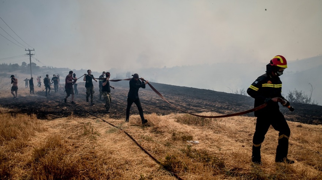 Πυροσβέστης και εθελοντές δασοπυροσβέστες στη μάχη της κατάσβεσης πυρκαγιάς στην Αττική