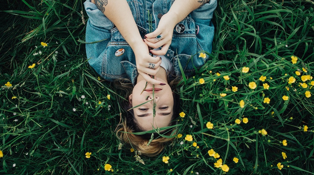 Μια γυναίκα ποζάρει ανάμεσα στα λουλούδια.