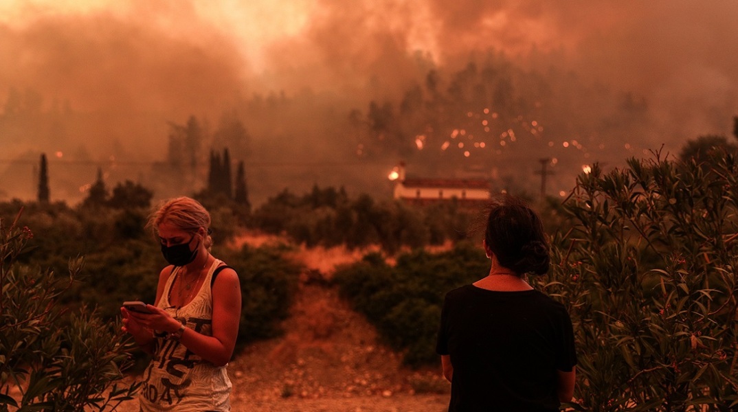 Δύο κάτοικοι παρακολουθούν τις φλόγες να φτάνουν στο χωριό Γούβες. 