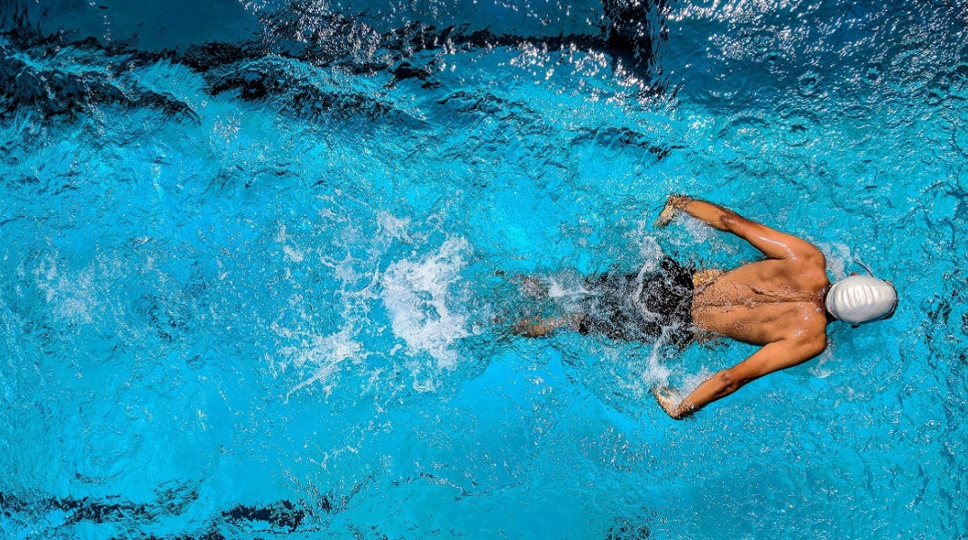 Ένας άντρας κολυμπάει σε μια πισίνα.
