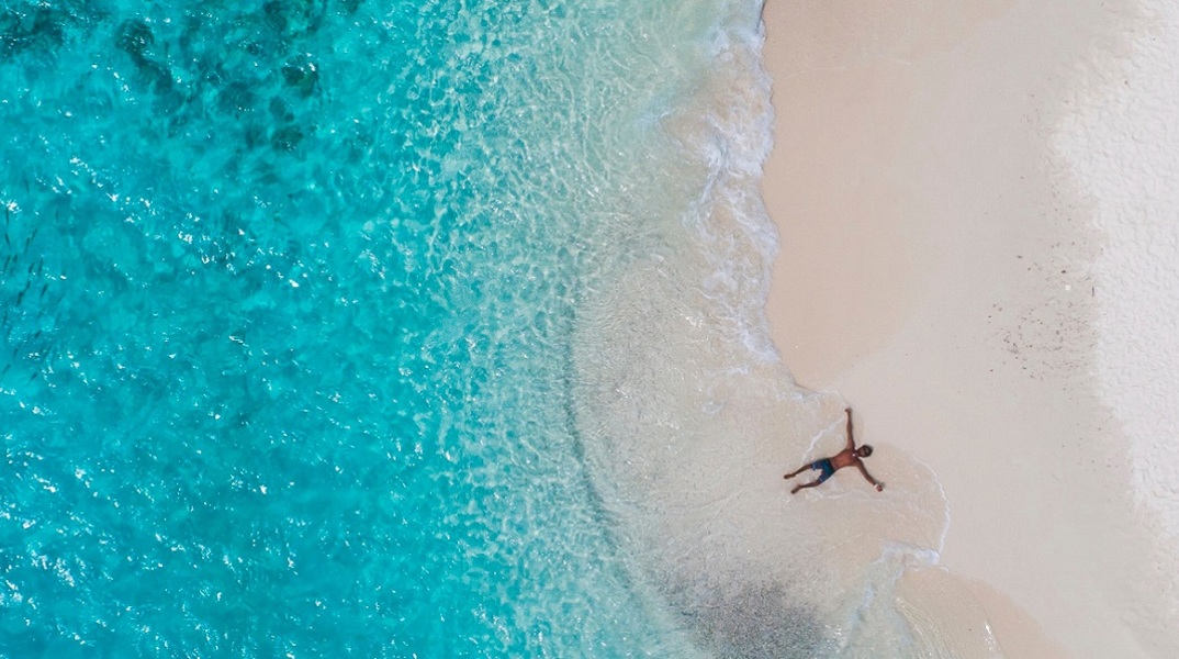 Ένας ανδρας ξαπλώνει στην παραλία και απολαμβάνει τη θάλασσα.