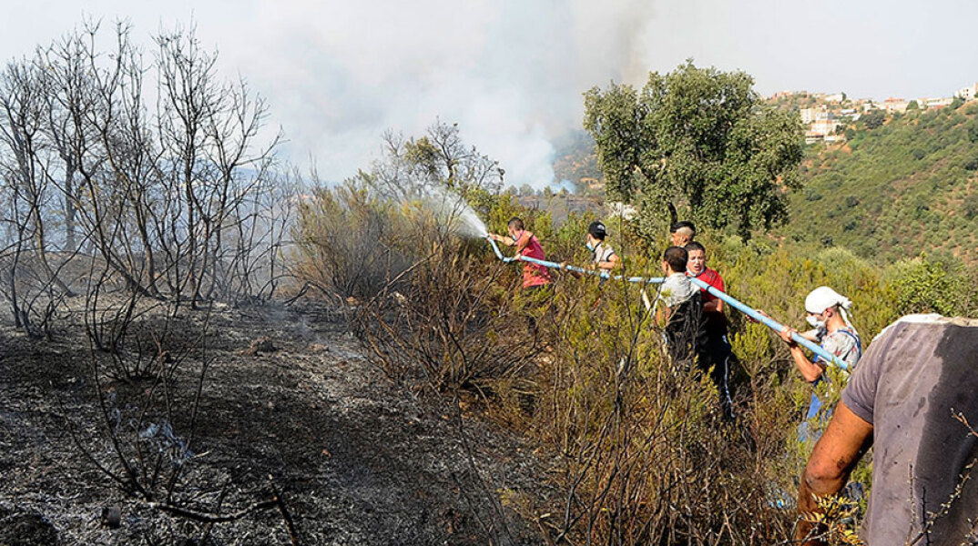 Στην Αλγερία, στην περιοχή Τίζι Ούζου, κάτοικοι και πυροσβέστες ρίχνουν με τη μάνικα νερό σε φωτιά