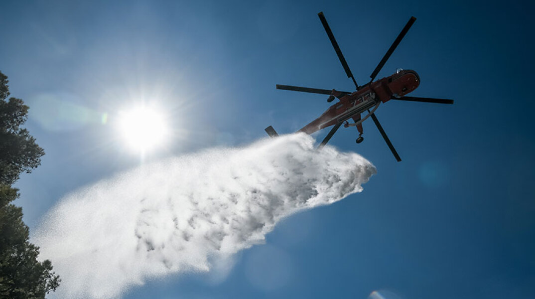 Ελικόπτερο πραγματοποιεί ρίψη νερού στην Κερατέα, όπου η φωτιά βρίσκεται σε ύφεση