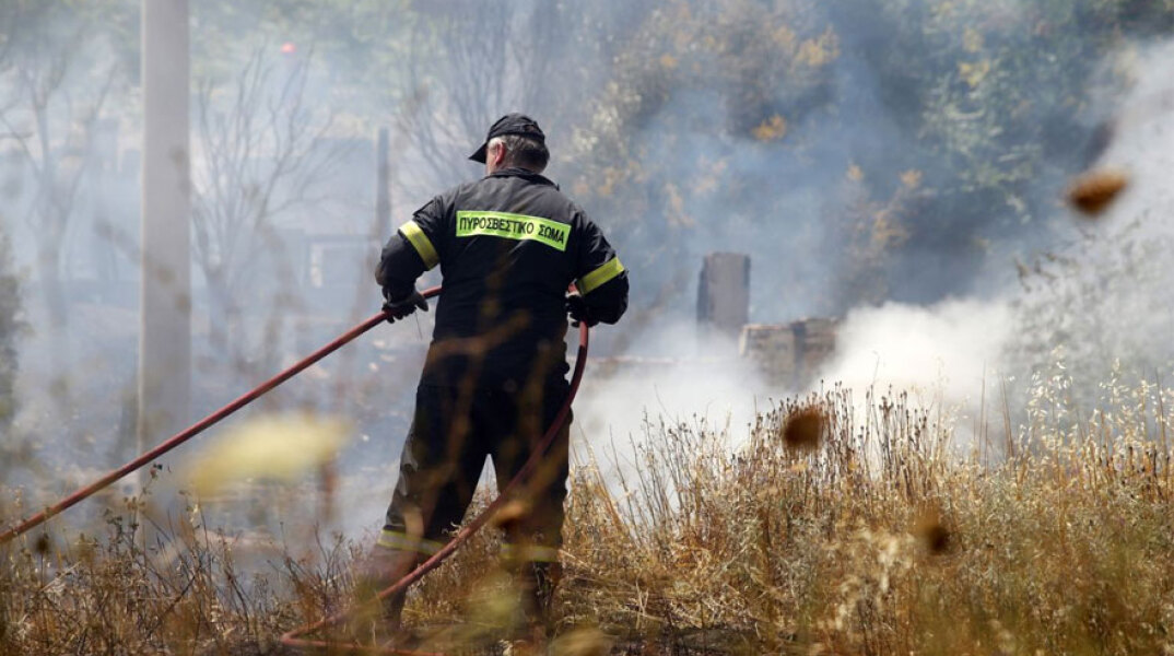Πυροσβέστης ρίχνει νερό σε φωτιά (ΦΩΤΟ ΑΡΧΕΙΟΥ) - Συναγερμός σε Αττική και Εύβοια καθώς είναι ακραίος ο κίνδυνος πυρκαγιάς την Κυριακή 22 Αυγούστου 2021