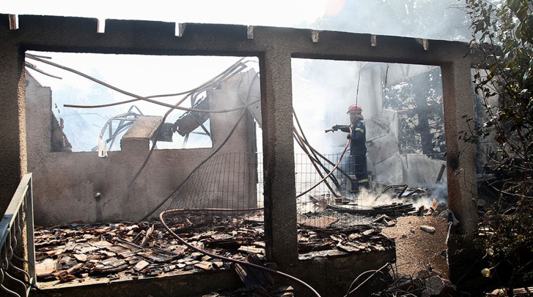 Καμένο κτίριο στα Βίλια, με πυροσβέστη να ρίχνει νερό - Σαρωτικό το πέρασμα της νέας φωτιάς