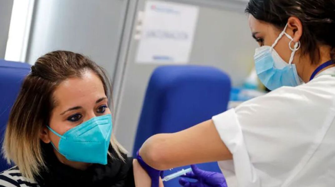 Γυναίκα με μάσκα για τον κορωνοϊό κάνει το εμβόλιο για την Covid-19 