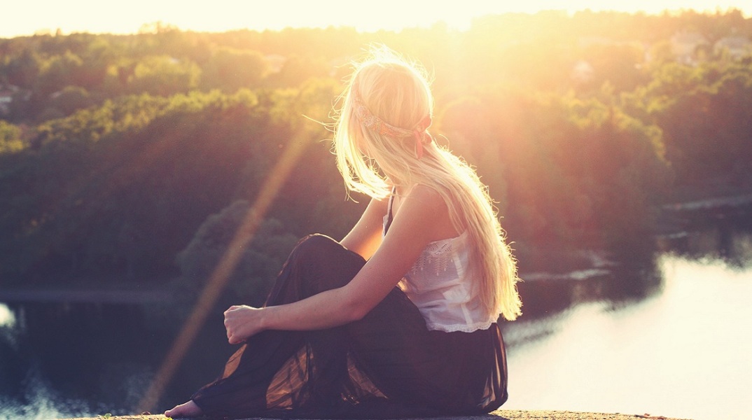 Ένα κορίτσι κάθεται και κοιτά μια λίμνη
