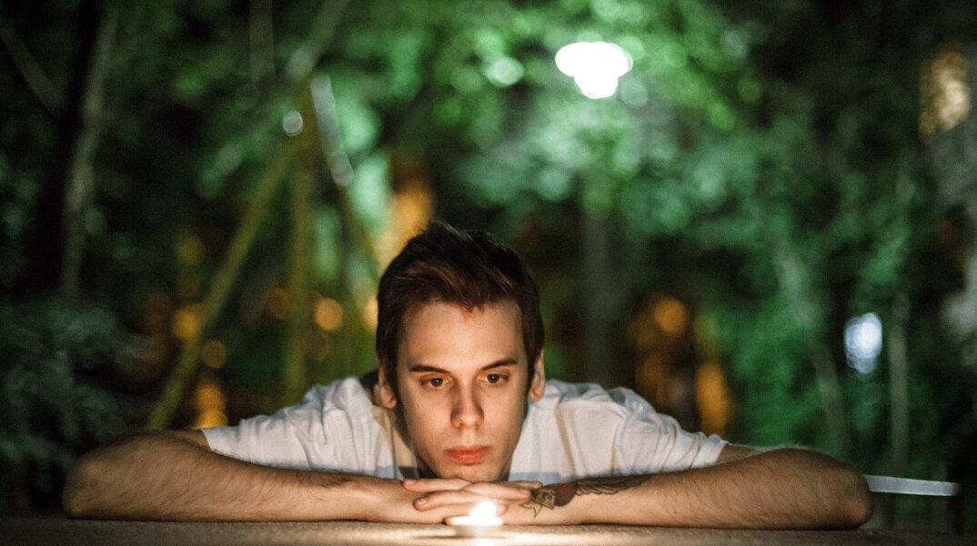 Άνδρας που είναι ξαπλωμένος και κοιτά αναμμένο κερί