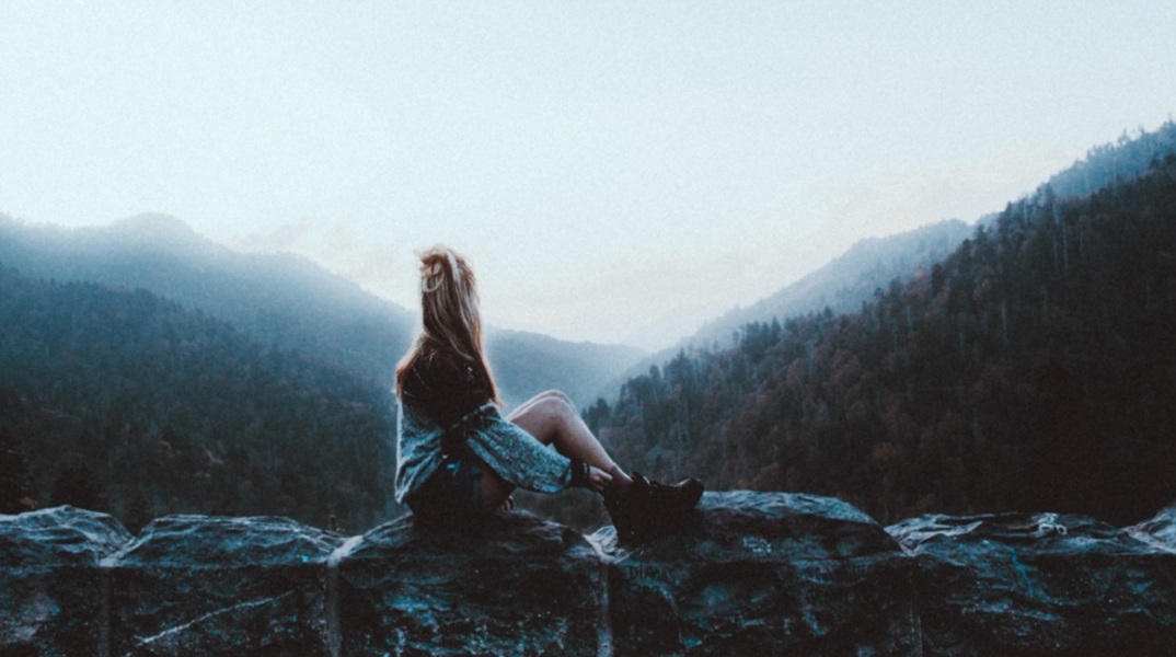 Μια κοπέλα κάθεται σε ένα βράχο 