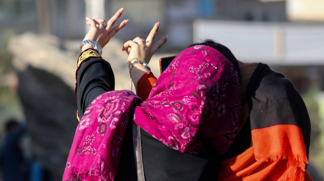 Γυναίκα με μαντήλα βγάζει σέλφι φωτογραφία σχηματίζοντας το σήμα της νίκης
