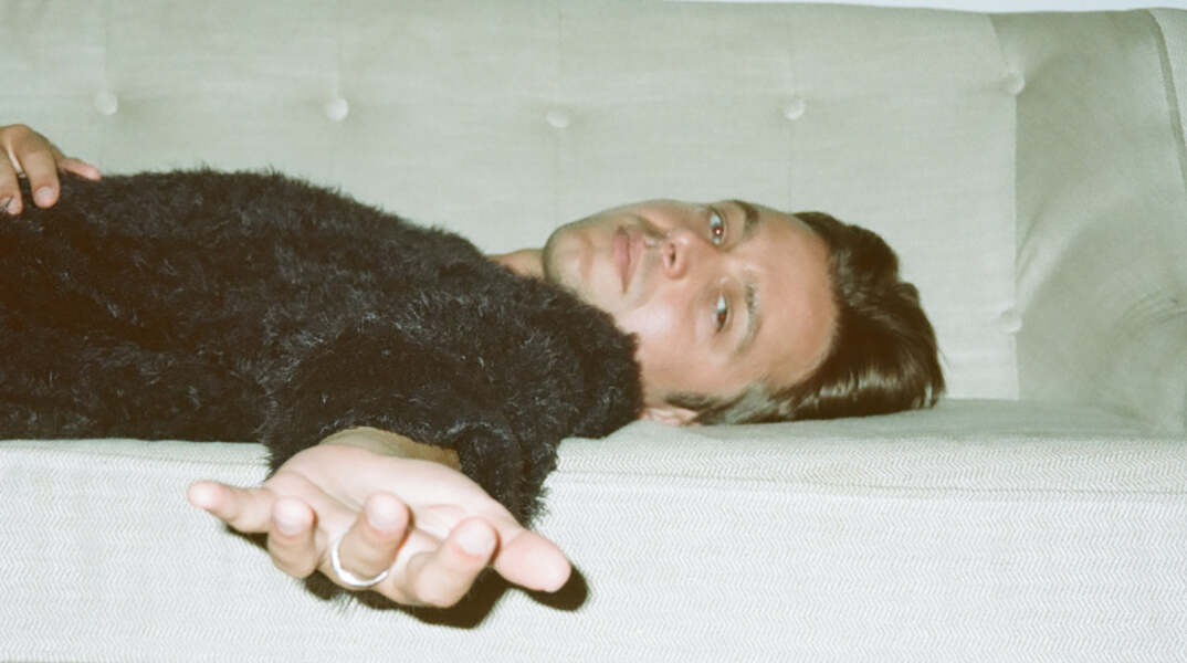 Ο τραγουδιστής George Cosby ξαπλωμένος σε καναπέ απλώνει το χέρι του