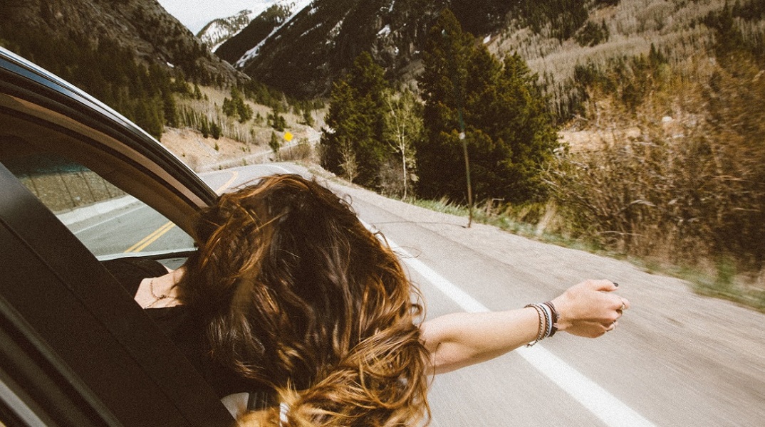 Μια κοπέλα βγάζει το χέρι από το παράθυρο κατά τη διάρκεια ενός roadtrip. 