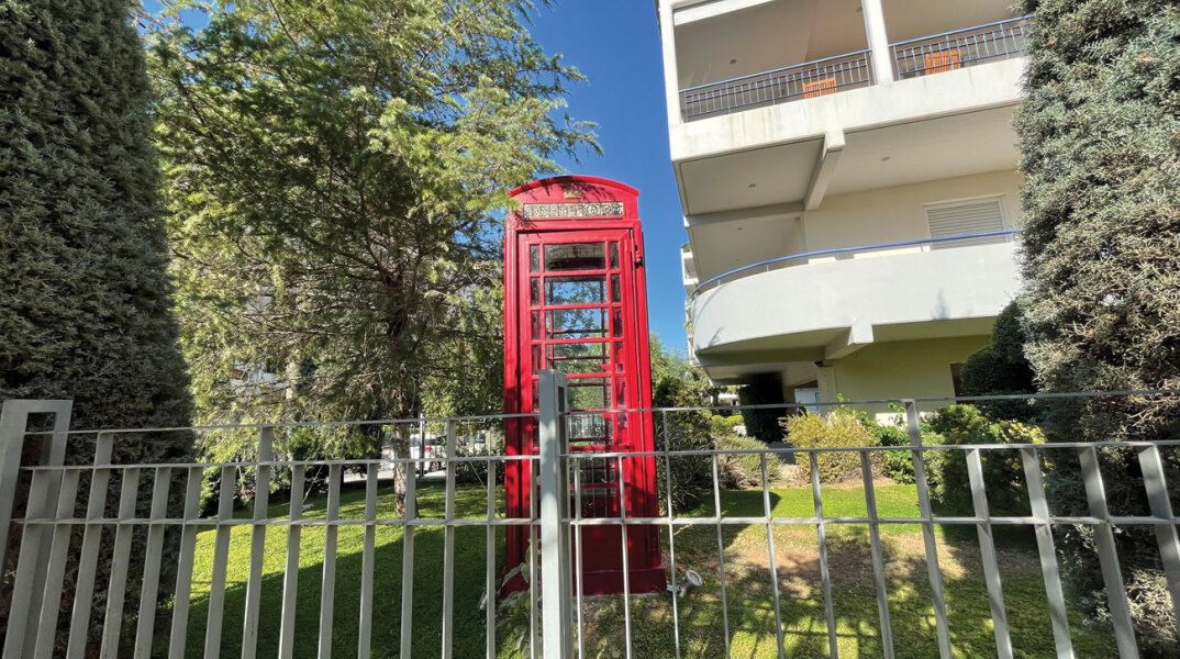 Κόκκινος τηλεφωνικός θάλαμος σε αυλή πολυκατοικίας στις Τζιτζιφιές