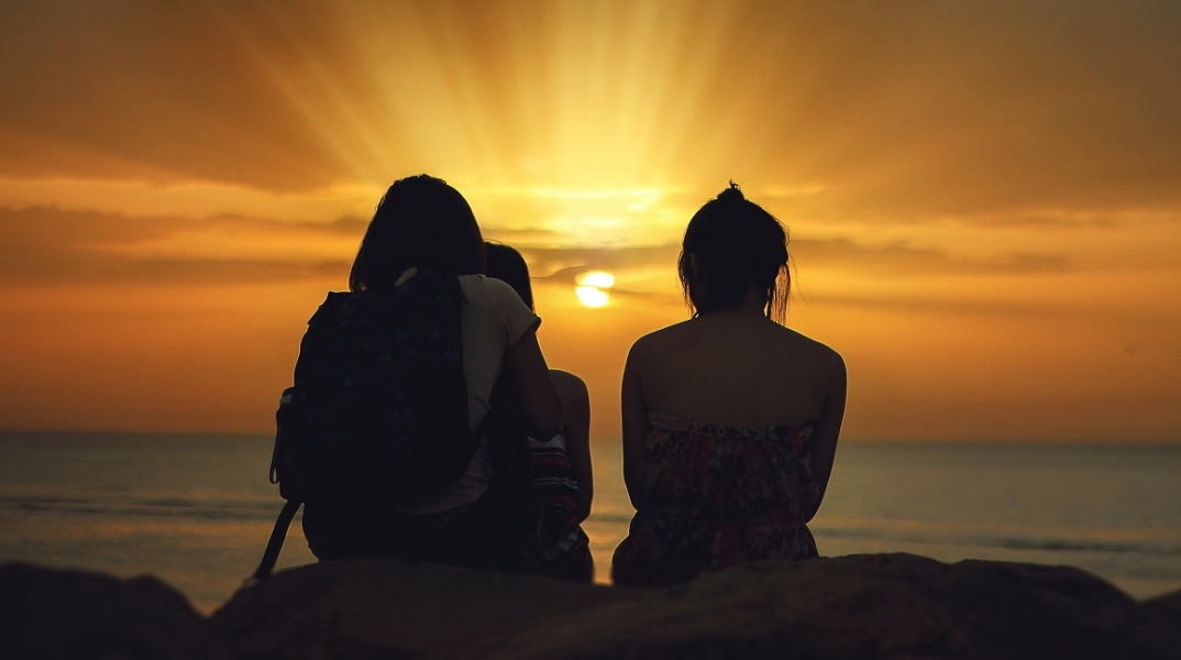 Τρία άτομα βλέπουν το ηλιοβασίλεμα 