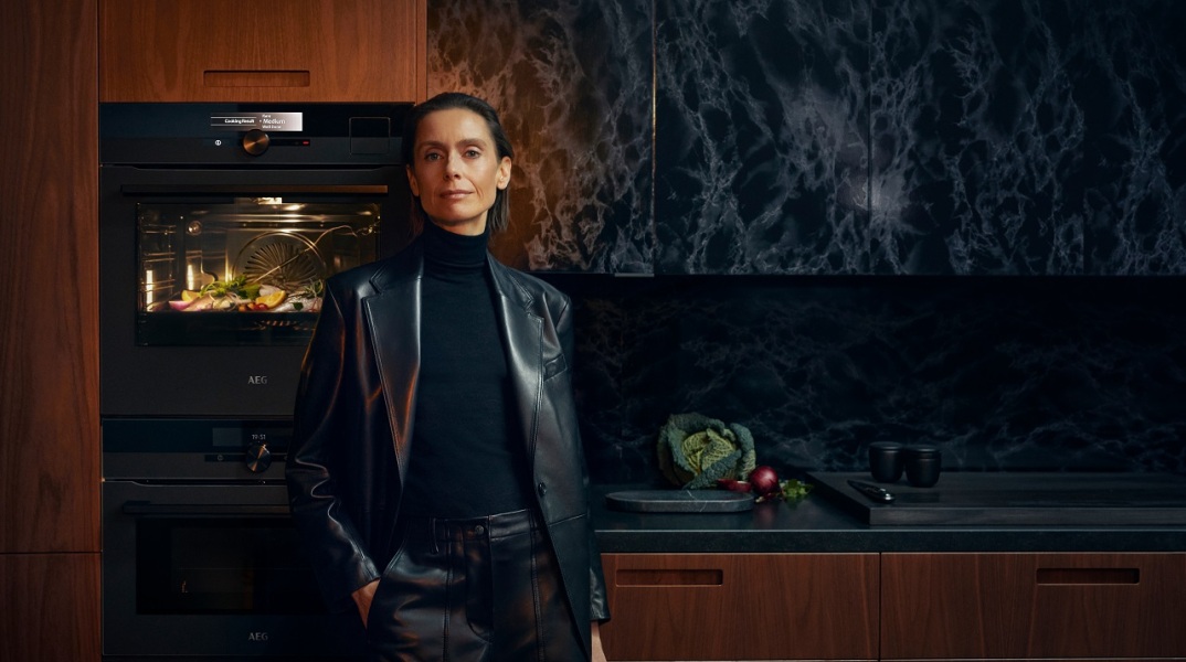Γυναίκα με μαύρα ρούχα στέκεται μπροστά από φούρνο AEG που λειτουργεί