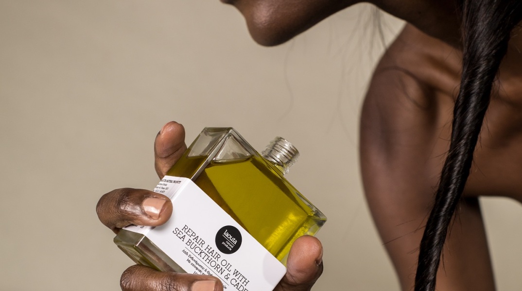 Μαύρη γυναίκα κρατάει μπουκαλάκι με έλαιο Laouta