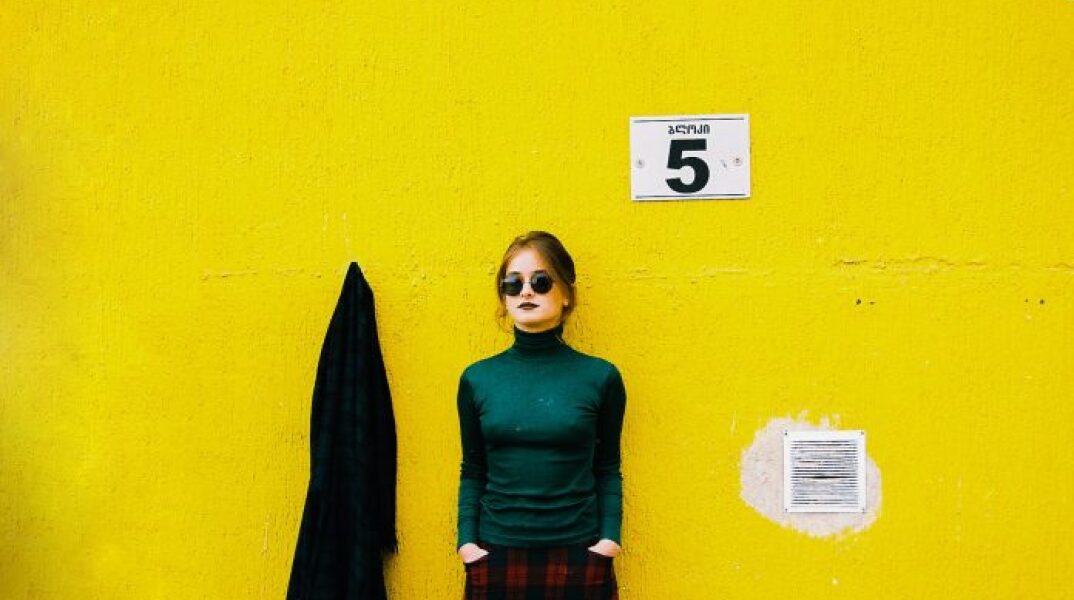 Γυναίκα που φορά γυαλιά ηλίου με φόντο κίτρινο τοίχο