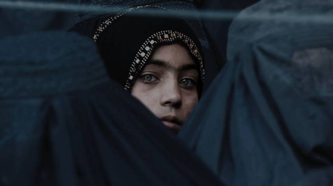 Ένα κορίτσι κοιτάζει ανάμεσα από άλλες Αφγανές γυναίκες 