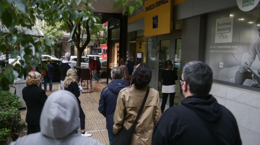 Πολίτες περιμένουν στην ουρά για να μπουν στην τράπεζα