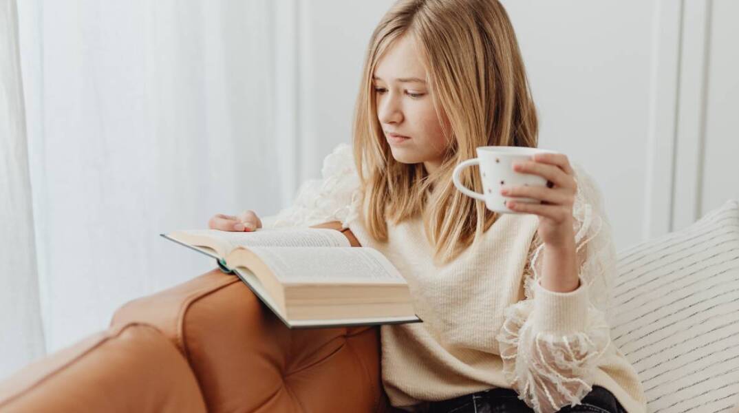 Νεαρή κοπέλα στον καναπέ, διαβάζει βιβλίο
