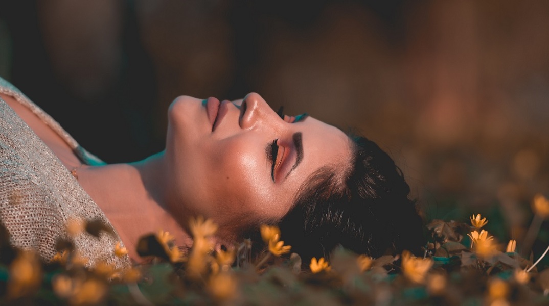 Ενα κορίτσι κάθεται στα χόρτα.