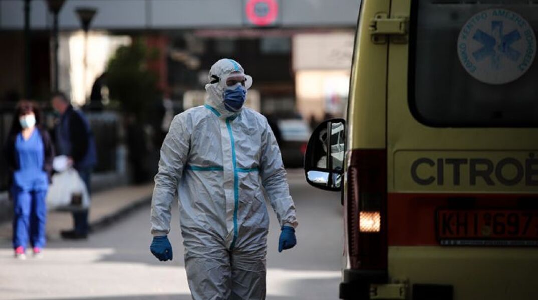 Τραυματιοφορέας με προστατευτική στολή για τον κορωνοϊό δίπλα σε ασθενοφόρο του ΕΚΑΒ 
