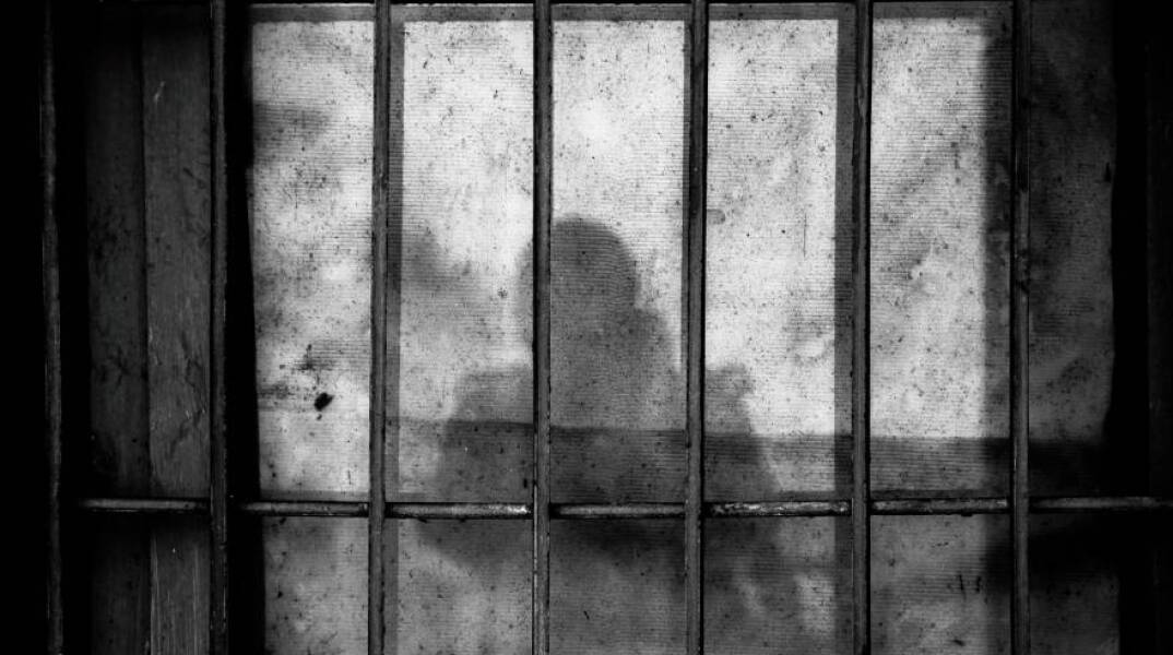 Σκιά στον τοίχο πίσω από τα κάγκελα της φυλακής