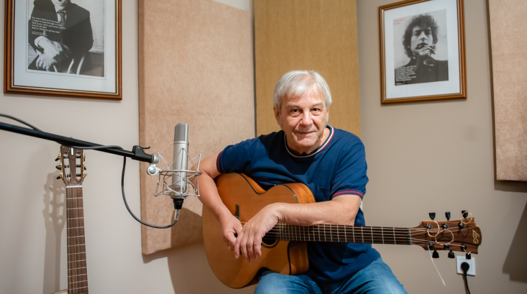 Ο Γιώργος Δημητριάδης κρατά ακουστική κιθάρα στο στούντιο